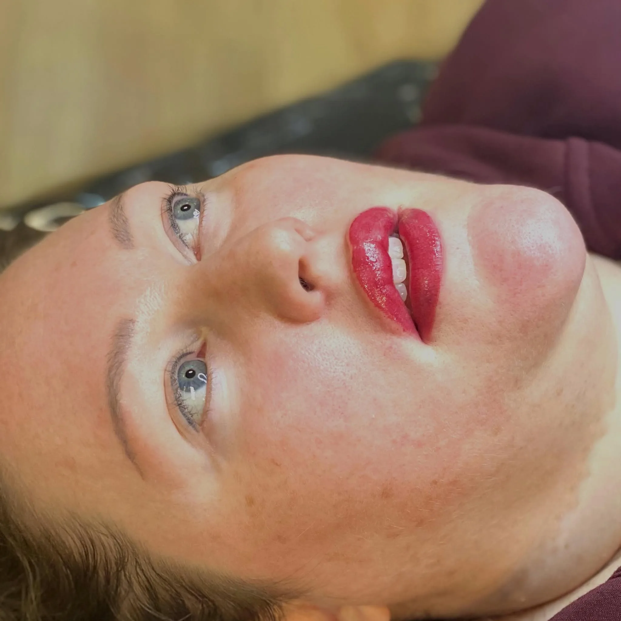 Reclining client with open eyes and healed red lip-blush result