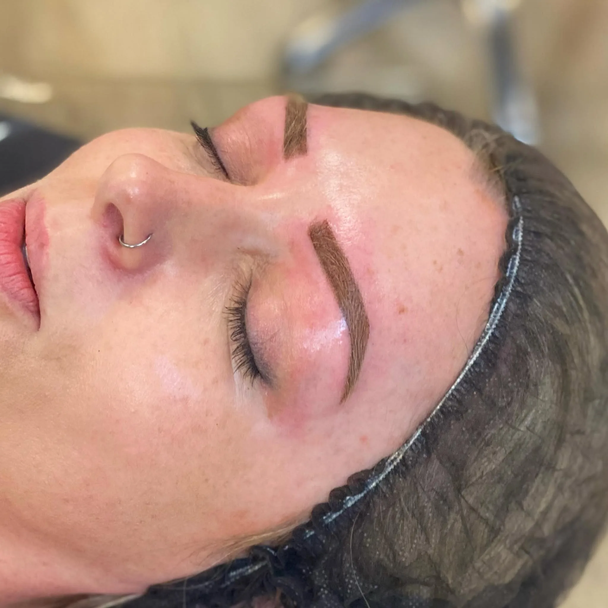 Reclining client with closed eyes and defined hair-stroke brows