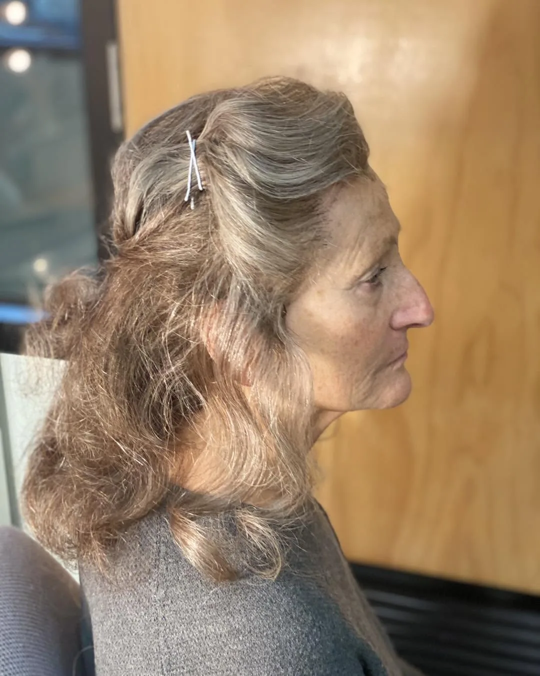Side profile — styled grey-blonde hair with salon interior behind